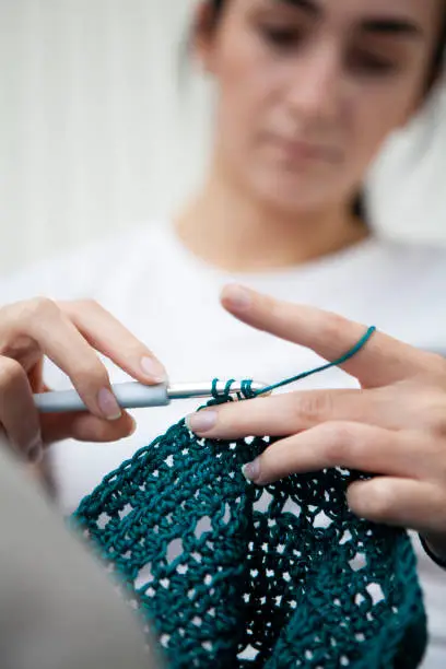 Low angle view of a teenager doing crochet with selective focus on the hands