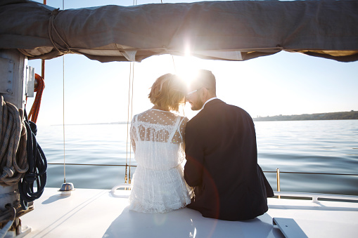 Beautiful wedding couple on yacht at wedding day outdoors in the sea. Beautiful elegant bride in a white dress and stylish groom on the luxury yacht sailing down the sea. Together. Wedding day.
