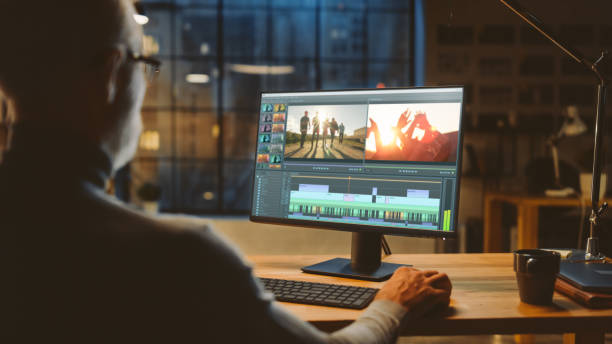 istock Over th Shoulder Shot: Professional Middle Aged Videographer Works on Desktop Computer, Doing Footage Montage, Using Video Editing Software. Modern Video Developers Office in the Evening 1269263314