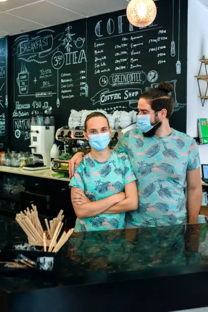 Coffee shop owners posing with masks looking to each other