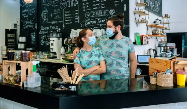 Coffee shop owners posing with masks looking to each other