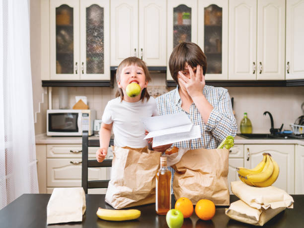 family sorts out purchases in the kitchen. father and son tastes products in bags made of craft paper. expensive healthy nutrition. - to do list organization life family imagens e fotografias de stock