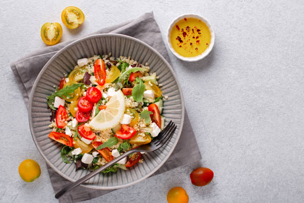 salat mit bulgur, kirschtomaten, fetakäse und grünen kräutern auf betontischplatte. nahöstlicher tabbouleh-salat, ansicht von oben - tabbouleh vegeterian food middle stock-fotos und bilder