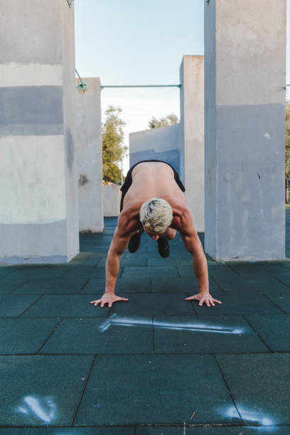 Young athletic man doing burpee on parkour area. Training alone outdoors. Young athletic man doing burpee on parkour area. Training alone outdoors burpee stock pictures, royalty-free photos & images