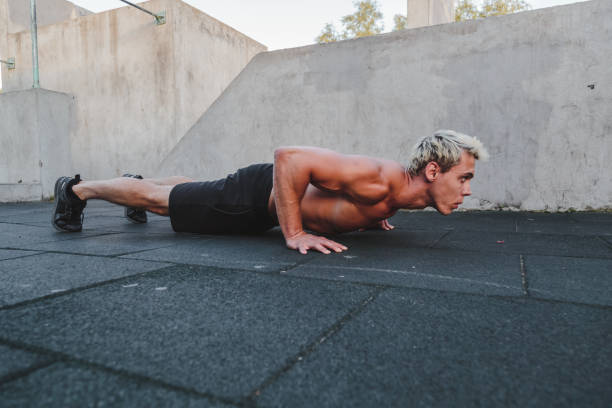 Young athletic man doing push ups on parkour area. Training alone outdoors. Young athletic man doing push ups on parkour area. Training alone outdoors. burpee stock pictures, royalty-free photos & images