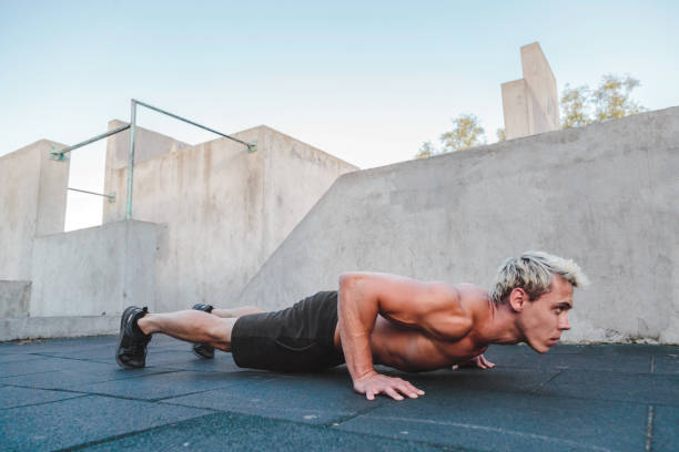 Young athletic man doing push ups on parkour area. Training alone outdoors. Young athletic man doing push ups on parkour area. Training alone outdoors burpee stock pictures, royalty-free photos & images