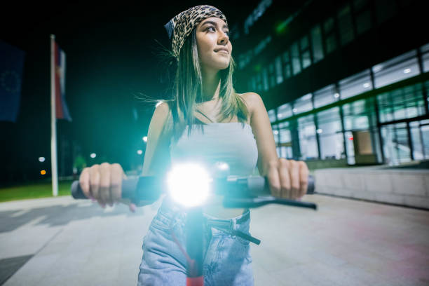 Young women is riding electric push scooter at night stock photo