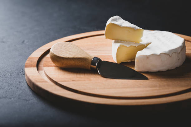 istock Sliced Camembert with knife on cheese platter on black background, 1269279994