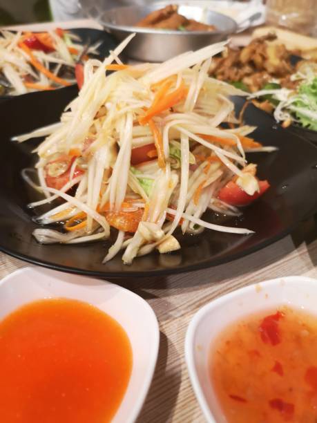 salade de papaye verte au piment tomate et ail, ajouter les crevettes servir avec des légumes sur la table, nourriture thaïlandaise goût aigre sucré épicé salé - sour taste green traditional culture lemon photos et images de collection