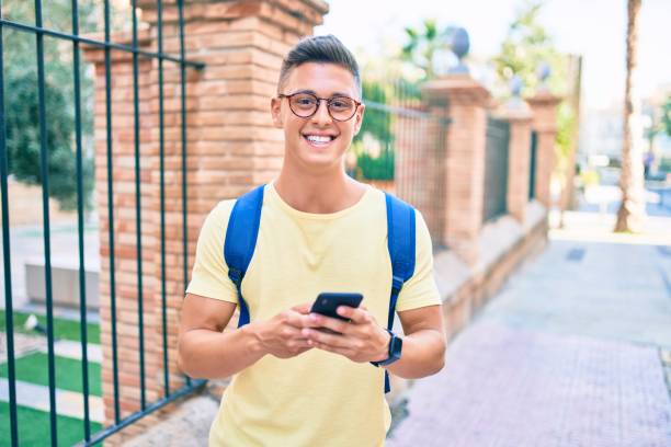 istock Young hispanic student smiling happy using smartphone walking at street o city 1269302281