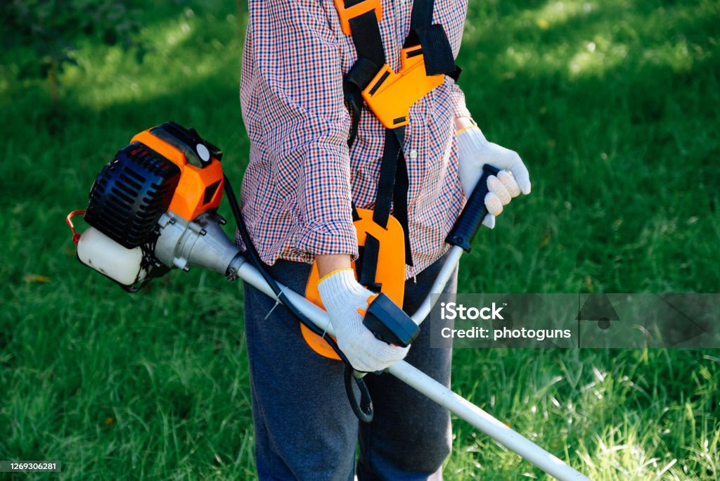 Female hands holding gasoline string trimmer, close-up view. Garden work concept. Lawn Mower Stock Photo