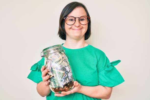 Brunette woman with down syndrome holding jar with savings smiling and laughing hard out loud because funny crazy joke. Brunette woman with down syndrome holding jar with savings smiling and laughing hard out loud because funny crazy joke. people laughing hard stock pictures, royalty-free photos & images