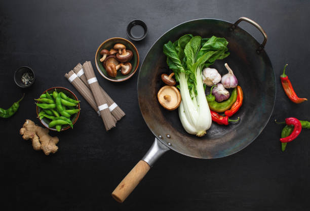 asiatische kulinarische zutaten mit wok auf dunkler oberfläche - chinesischer senfkohl stock-fotos und bilder
