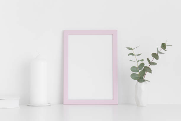 istock Pink frame mockup with workspace accessories and eucalyptus in a vase on a white table. Portrait orientation. 1269324629