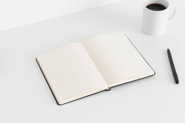 istock Open notebook mockup with a cup of coffee and a pen on a white table. 1269324792