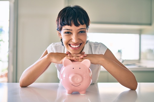 Young brunette woman smiling happy showing proud piggy bank with savings
