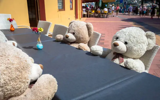 A group of Teddy Bears sitting at the a table and ready for a lunch or a meeting