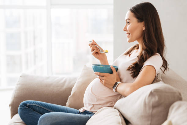 Jeune femme enceinte de sourire ayant le petit déjeuner sain - Photo