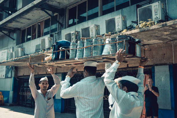 Mumbai, India, 18 november, 2019 / Dabbawala lunchbox delivery service: operators with typical whitehat delivering lunchboxes with warm food. Operators transporting the boxes