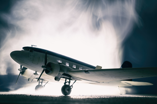 A classic DC-3 Dakota sits on a runway with mist/fog swirling around it. Model photography.