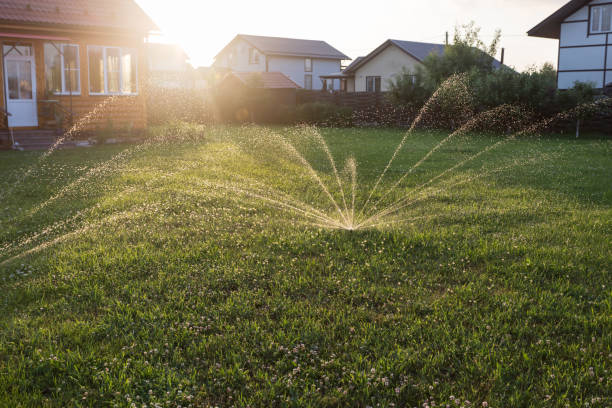 Automatic sprinkler system watering the lawn on the sunset Automatic sprinkler system watering the lawn on the sunset agricultural sprinkler stock pictures, royalty-free photos & images