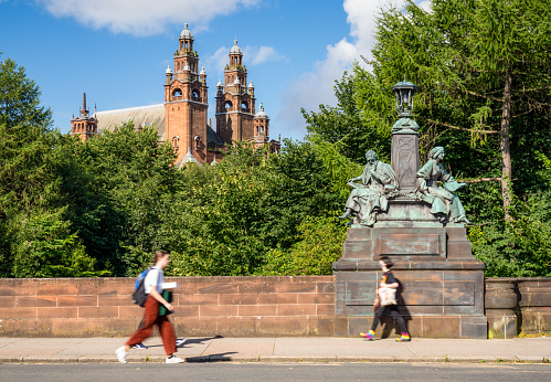 Glasgow, Scotland - People crossing Kelvin Way Bridge in Glasgow's West End, with the towers of Kelvingrove Museum and Art Gallery on the horizon.