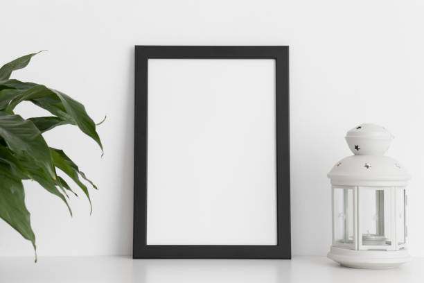 istock Black frame mockup with a spathiphyllum and candle holder on a white table. Portrait orientation. 1269334301