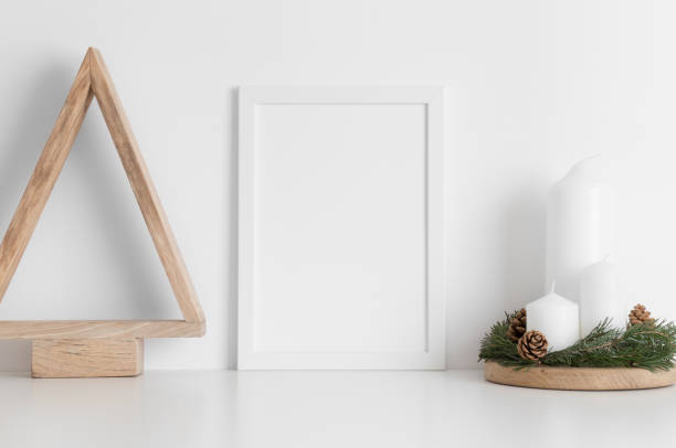 istock White frame mockup with a wooden tree and candles on a white table. Christmas decoration. 1269335440