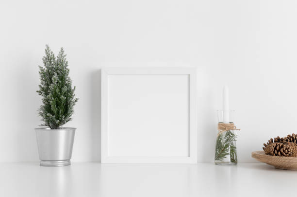 istock White square frame mockup with a cypress tree, candles and pine cones on a white table. Christmas decoration. 1269335466