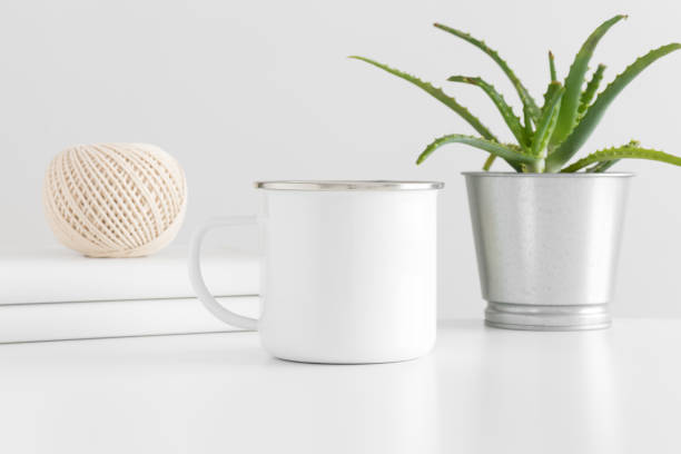 istock Enamel mug mockup with workspace accessories and a succulent plant on a white table. 1269335817