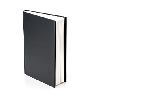 Front view of a black hard cover book standing on white background. The book is at the left of an horizontal frame leaving useful copy space for text and/or logo at the right. High resolution 42Mp studio digital capture taken with SONY A7rII and Zeiss Batis 40mm F2.0 CF lens