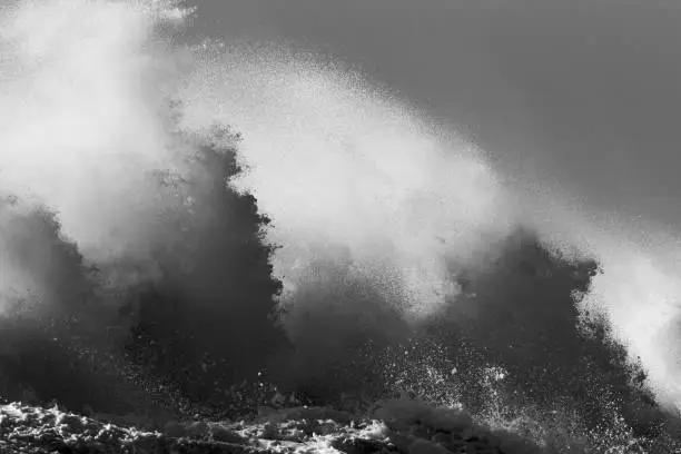 Black-and-white image of huge waves crashing over the pier of Ijmuiden, Netherlands during severe coastal storm. Panoramic view of the North Sea in the Netherlands.