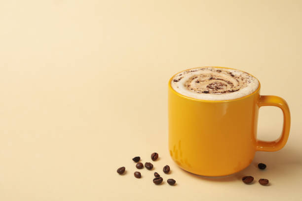 istock Cup of latte and coffee seeds on beige background 1269347168