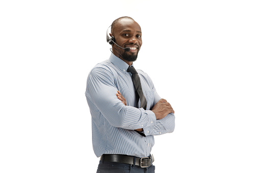 Talking and smiling, hands crossed. Young african-american call center consultant with headset on white background. Copyspace for ad, text. Concept of professional occupation, work, job, communication.