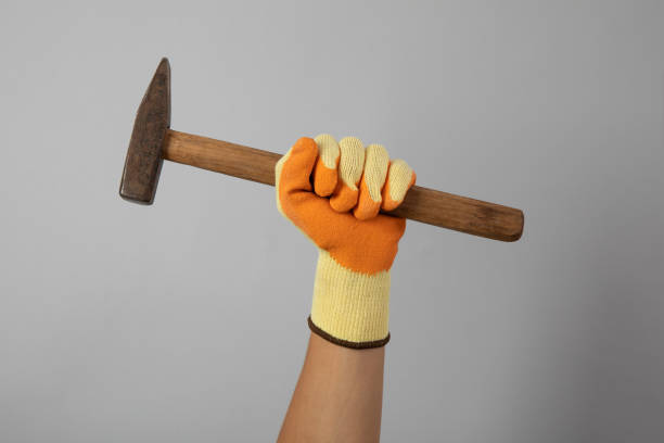 Hand in construction glove hold hammer on gray background
