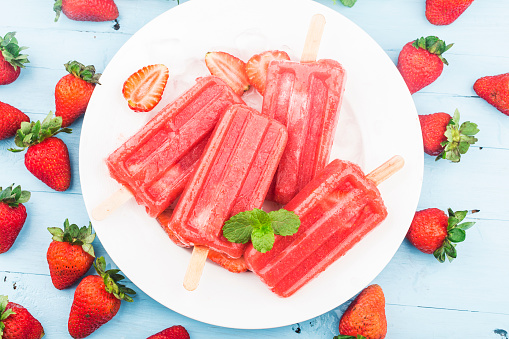 Homemade strawberry popsicles with ice and berries.