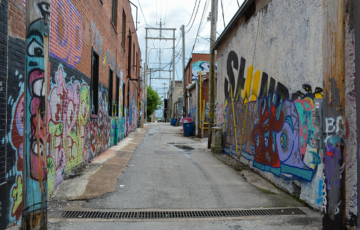 Young Mexican woman creating outdoor mural on the roof top wall. She is dressed in casual outfit. Exterior of old building in the city of Toronto, Canada..