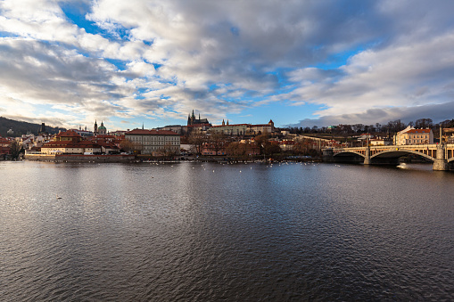 Beautiful view of Mala Strana old district of Prague on the Vltava river side with Wallenstein Palace and Prague Castle, on sunny winter day with blue sky and cloud,  Czech Republic