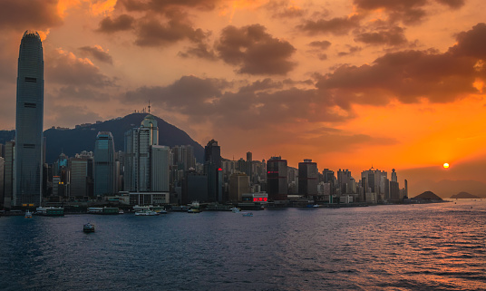 Orange glow of setting sun over Victoria Harbour and the West Side of Central on Hong Kong Island, overlooked by Victoria Peak.