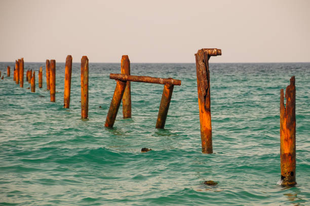 istock Seascape with blue calm water and rows of Rusty pipes with green algae on summer day. Rusty pipes remaining from old pier. Perspective leading to horizon, no people. Calm water. 1269365446
