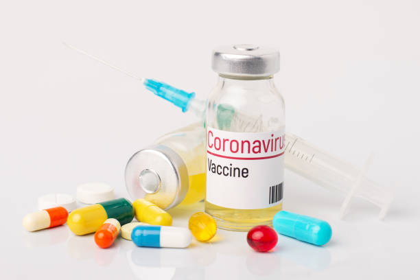 istock Ampule with coronavirus vaccine and many pills on white table 1269366434