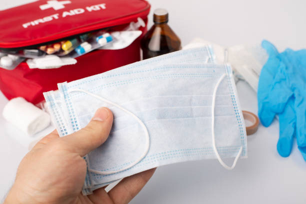 istock Man holding medical masks against first aid kit. 1269366448