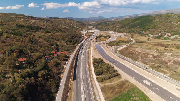 istock Multiple lane road curves through hilly landscape. Sky and clouds. Sunny. 1269367086