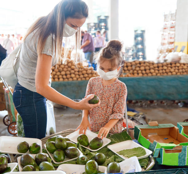 バザー市場から果物を買う母と娘 - two pears ストックフォトと画像