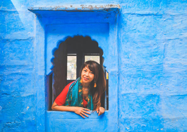 istock Asian woman looking out blue windows frame in Jodhpur, India 1269370955