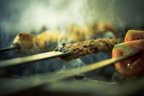 Cooking Turkish traditional adana kebab with tomatoes on grill