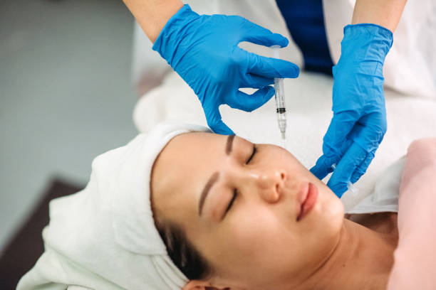 Asian chinese female receiving injection on the face at facial beauty salon stock photo