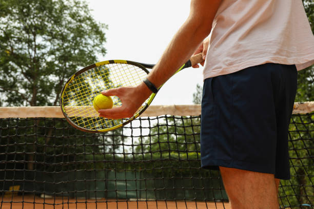 istock Man hold racket and ball against tennis net 1269375417