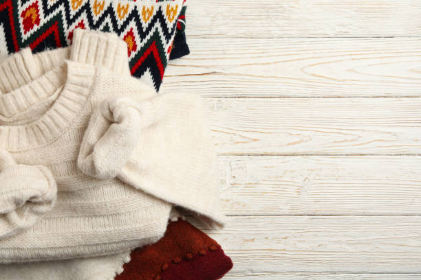 istock Knitted sweaters on white wooden background, space for text 1269378439