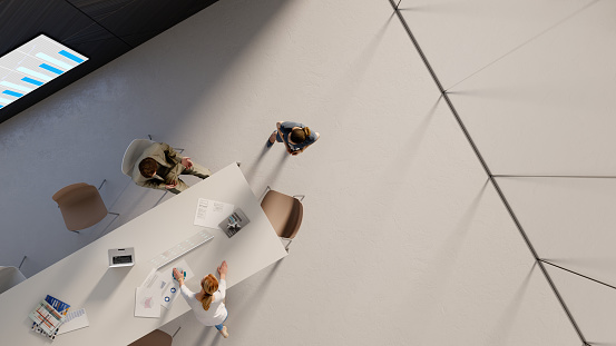 Overhead view of three people working in the office. All elements in the scene are 3D